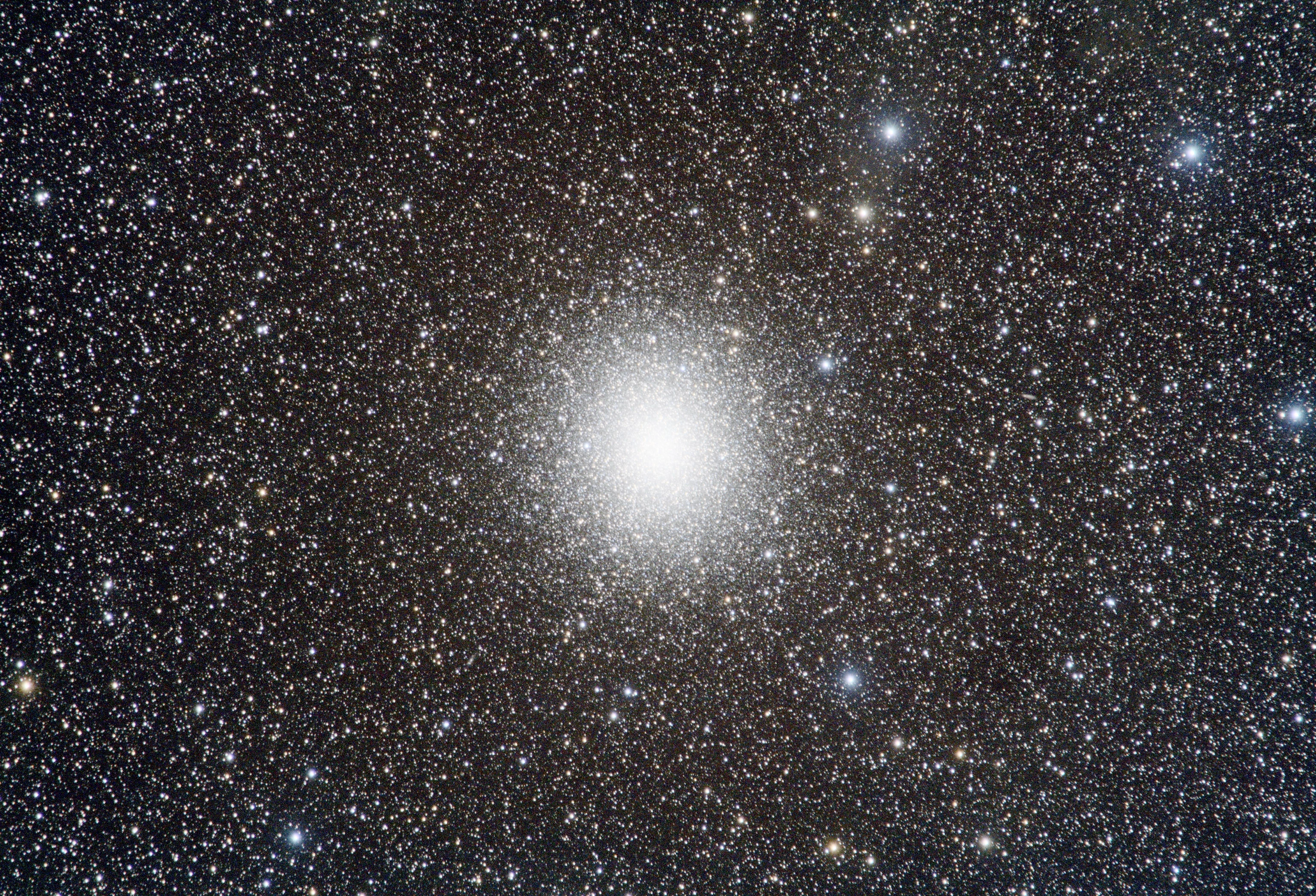 A fuzzy orb made up out of uncountable little dots of light. As you near the center, the dots become indistinguishable and form a single bright mass.

All this set set on a dense background of stars of varying size and colour.