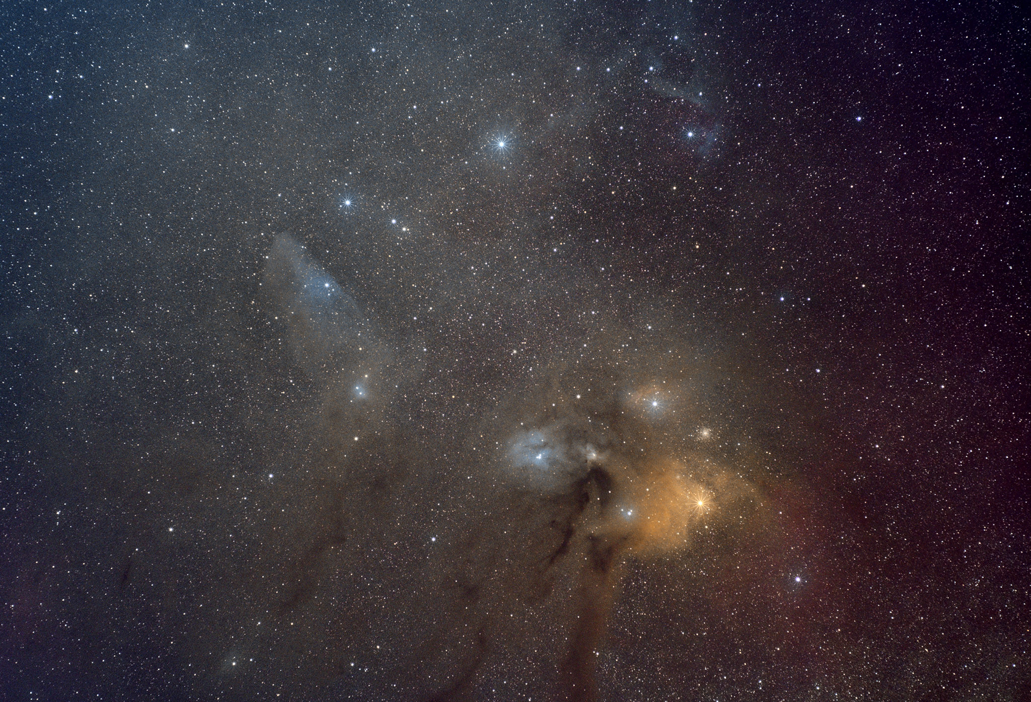 A wide view of starry space in the head of the Scorpion, covered in various dark and coloured light nebulae. A few very bright stars and fuzzy globular clusters are scattered around. Notably bright orange Antares at bottom right.